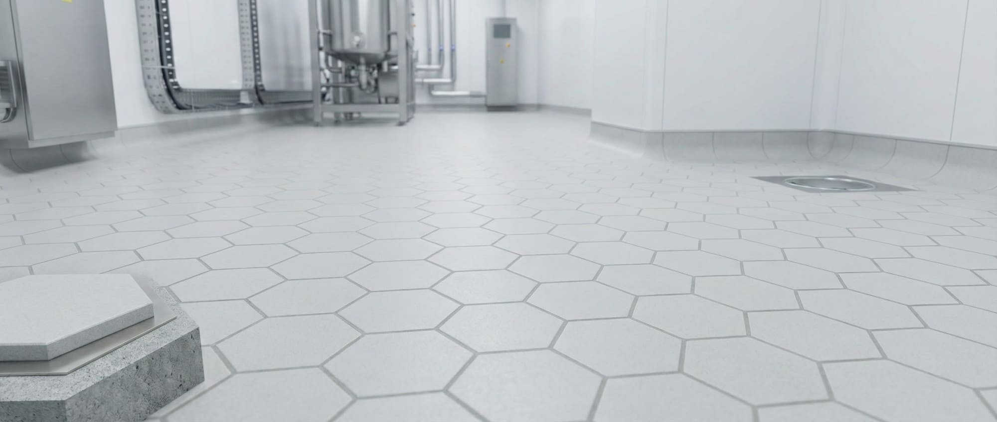 Froschperspektive eines sterilen Reinraums mit Grindingfloor Pharmafloor aus hellen Hexacer Sechseckfliesen - Edelstahltanks im Hintergrund - Darstellung der bündigen Fugen für maximale Hygiene in der Pharmaindustrie.