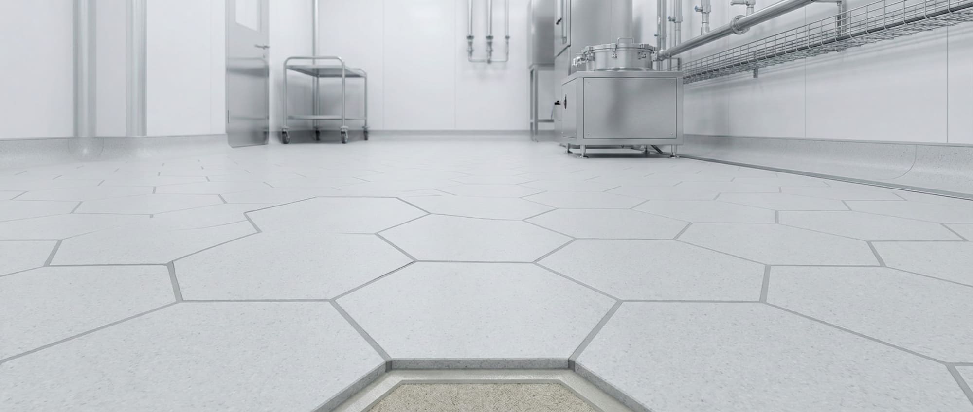 Froschperspektive eines sterilen Reinraums mit Grindingfloor Pharmafloor aus Hexacer Sechseckfliesen - im Vordergrund Querschnitt des Bodenaufbaus zur Darstellung der Fugenintegrität und Ableitfähigkeit.
