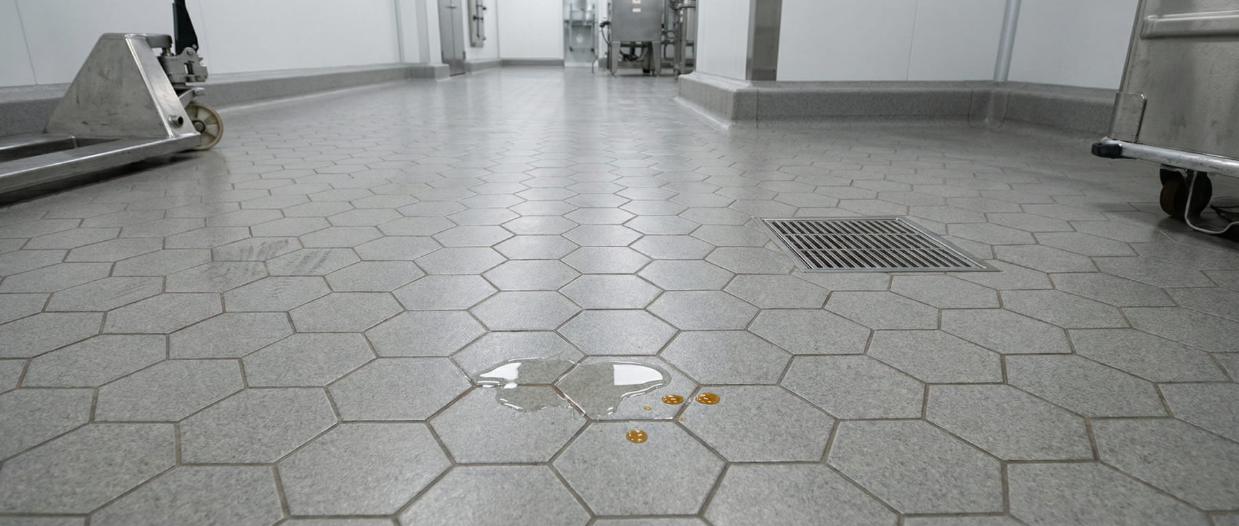 Graue Hexacer Keramikfliesen in einem Pharmaraum mit verschütteter Flüssigkeit und Edelstahl-Gerät - Visualisierung von säurefesten Böden für die chemische Industrie.