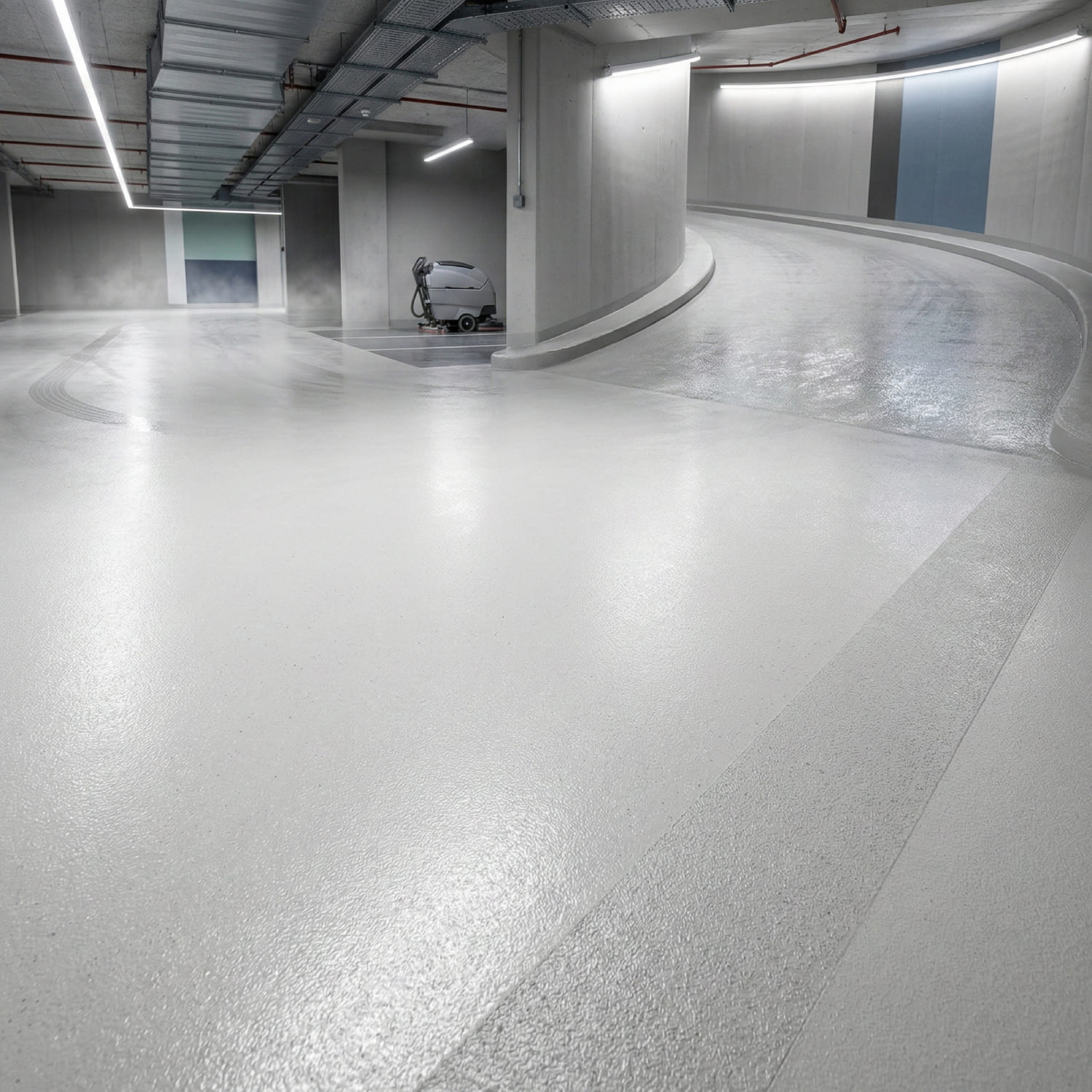 Helle Tiefgarage mit kurviger Auffahrtsrampe und rutschfestem Bodenbelag sowie einer Reinigungsmaschine im Hintergrund - Visualisierung von Phase 3 Funktionales Finish und Rutschsicherheit.