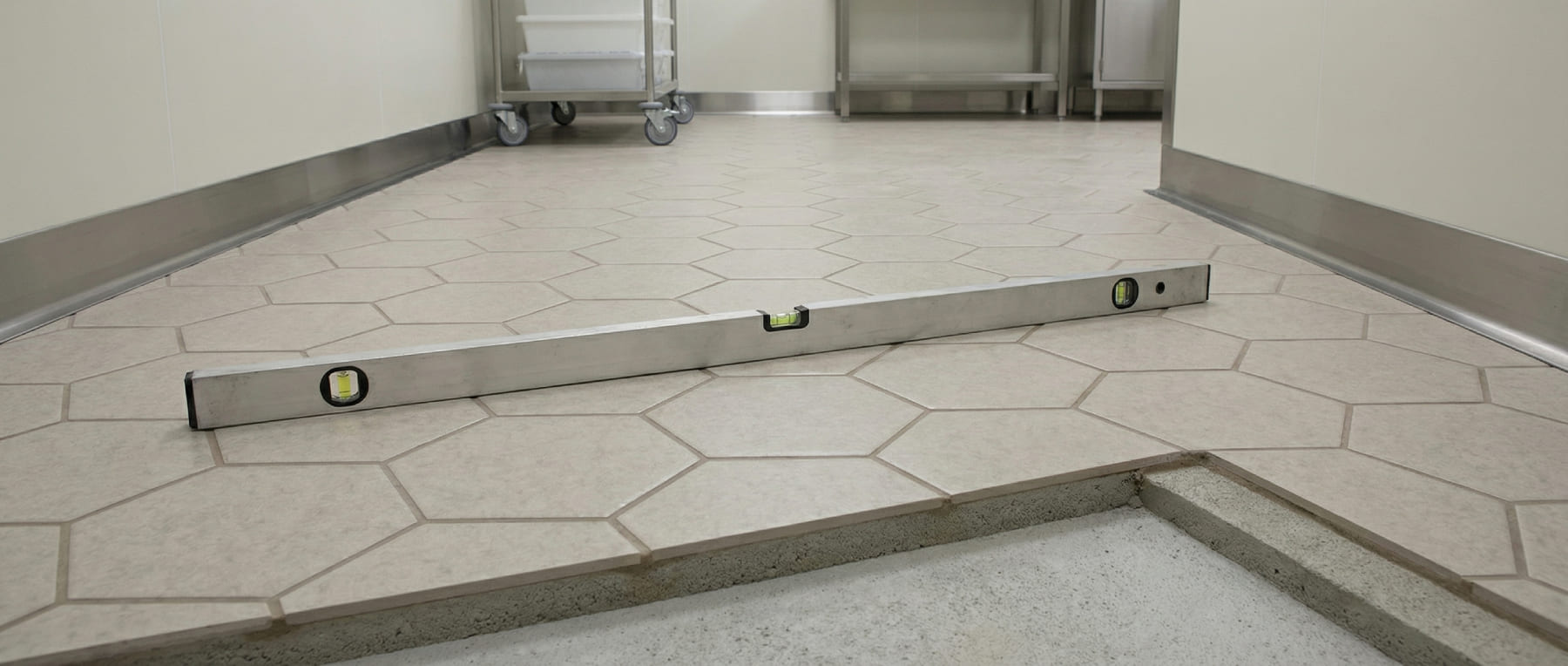 Wasserwaage auf geschliffenen Hexacer-Fliesen zur Prüfung der Ebenheit - Querschnitt zeigt den Aufbau nach AGI-Arbeitsblatt S40 - Visualisierung konstruktiver Normen.