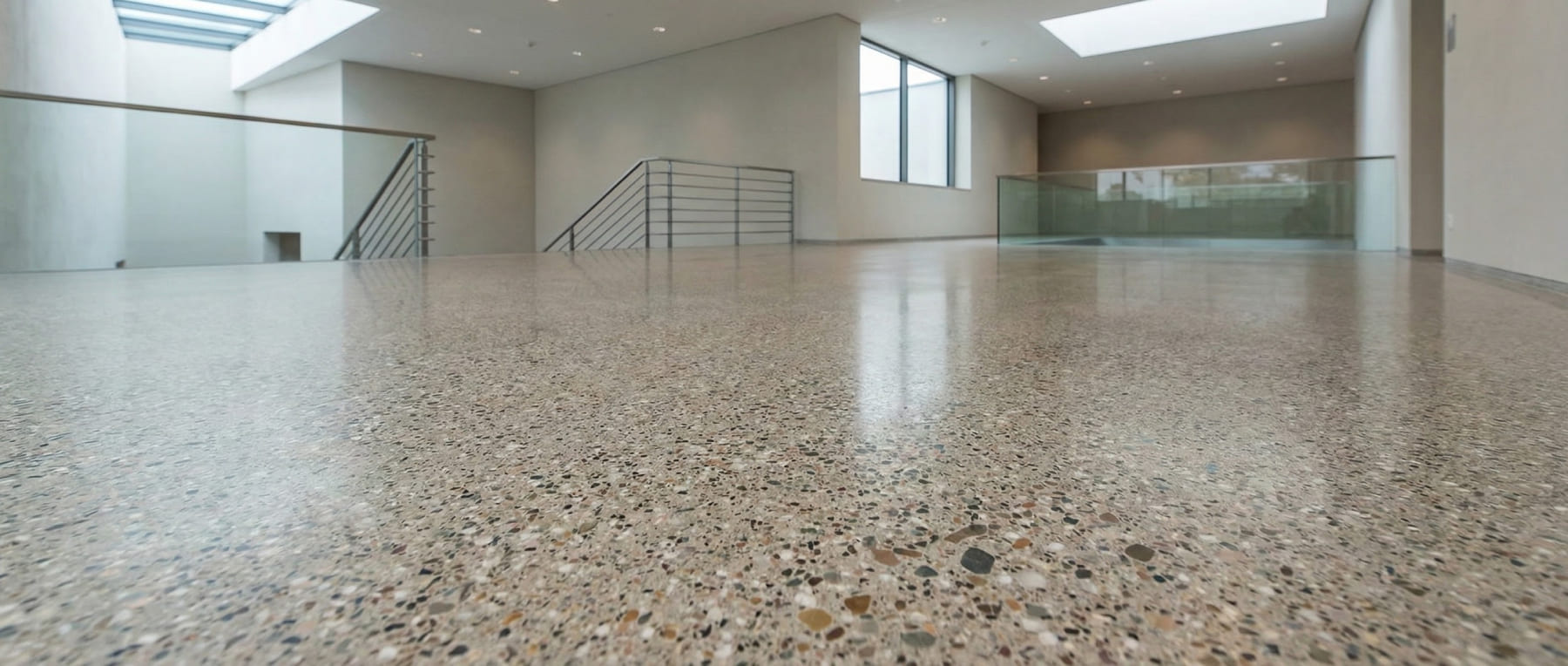 Froschperspektive eines lichtdurchfluteten Foyers mit geschliffenem Sichtestrich in Terrazzo-Optik und freigelegtem Grobkorn - Visualisierung der exklusiven Anmutung für Museen und Showrooms.