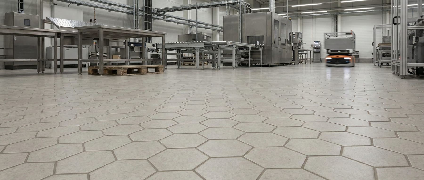 Blick auf einen Hexacer Industrieboden mit sechseckigen Fliesen in einer Produktionshalle mit FTS Roboter und Edelstahlmaschinen - Visualisierung der Volumenleitfähigkeit ohne Beschichtung.